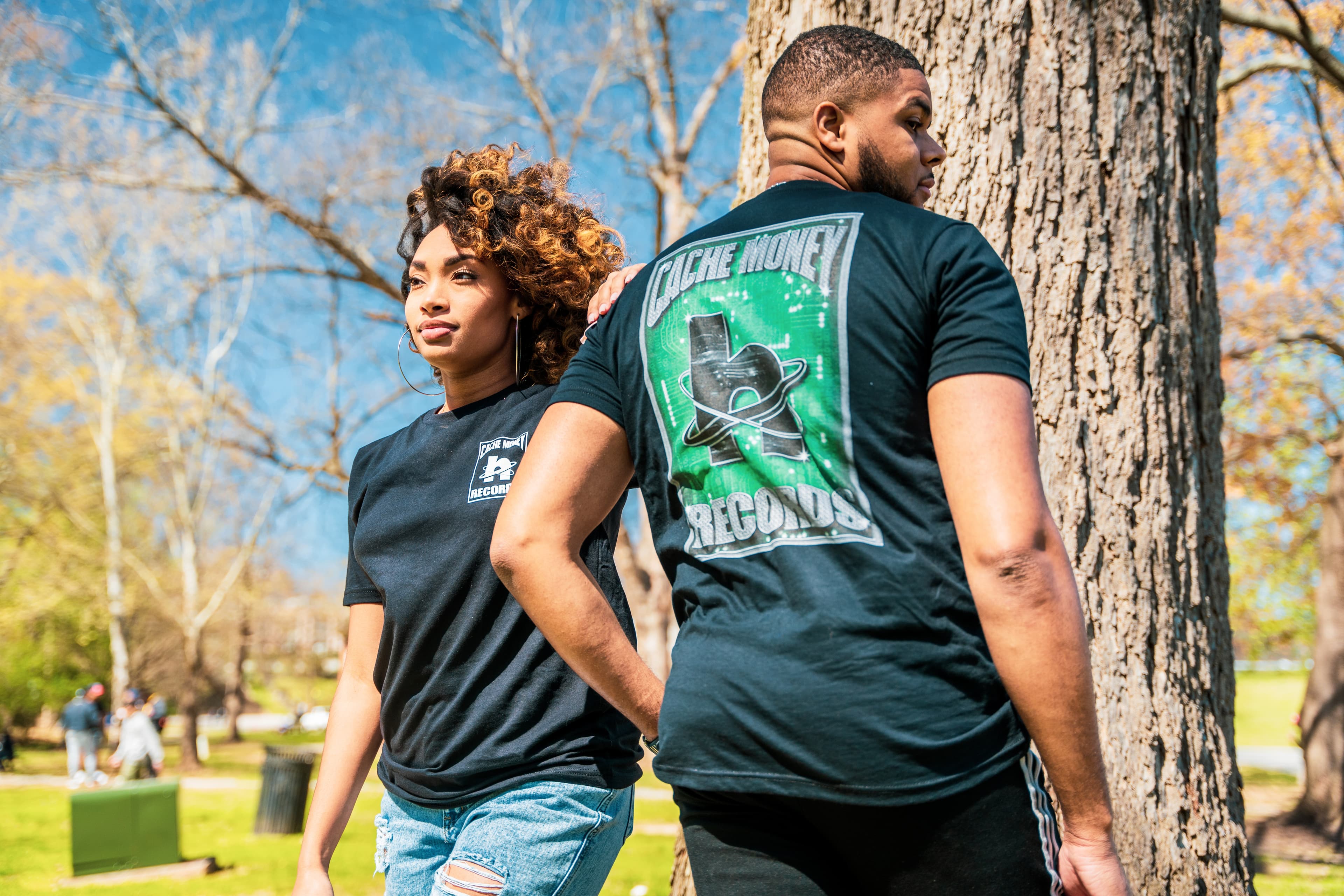 Photo of two people wearing render merch that says cache money in a punny way